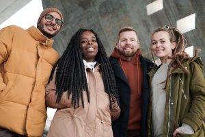 Friends enjoying winter outdoors, dressed warmly and smiling at the camera.